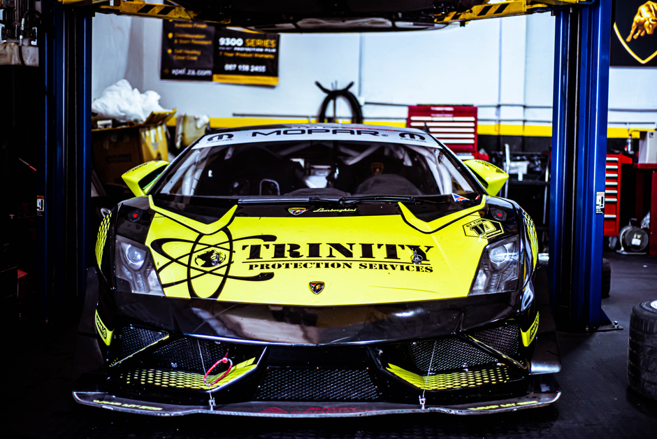 Front view of a vibrant yellow Lamborghini race car in an auto workshop, ready for action.