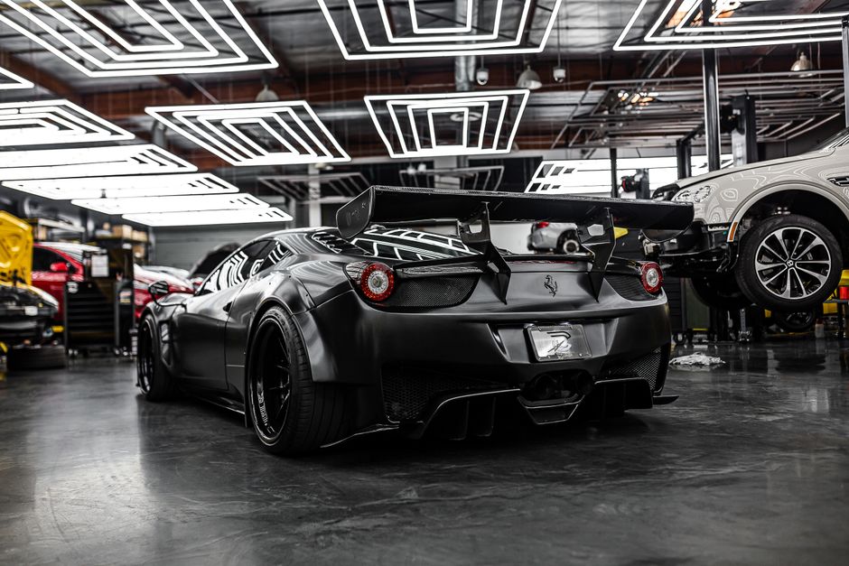 Sleek black sports car with spoiler in a modern, illuminated garage setting. Perfect for luxury automotive themes.